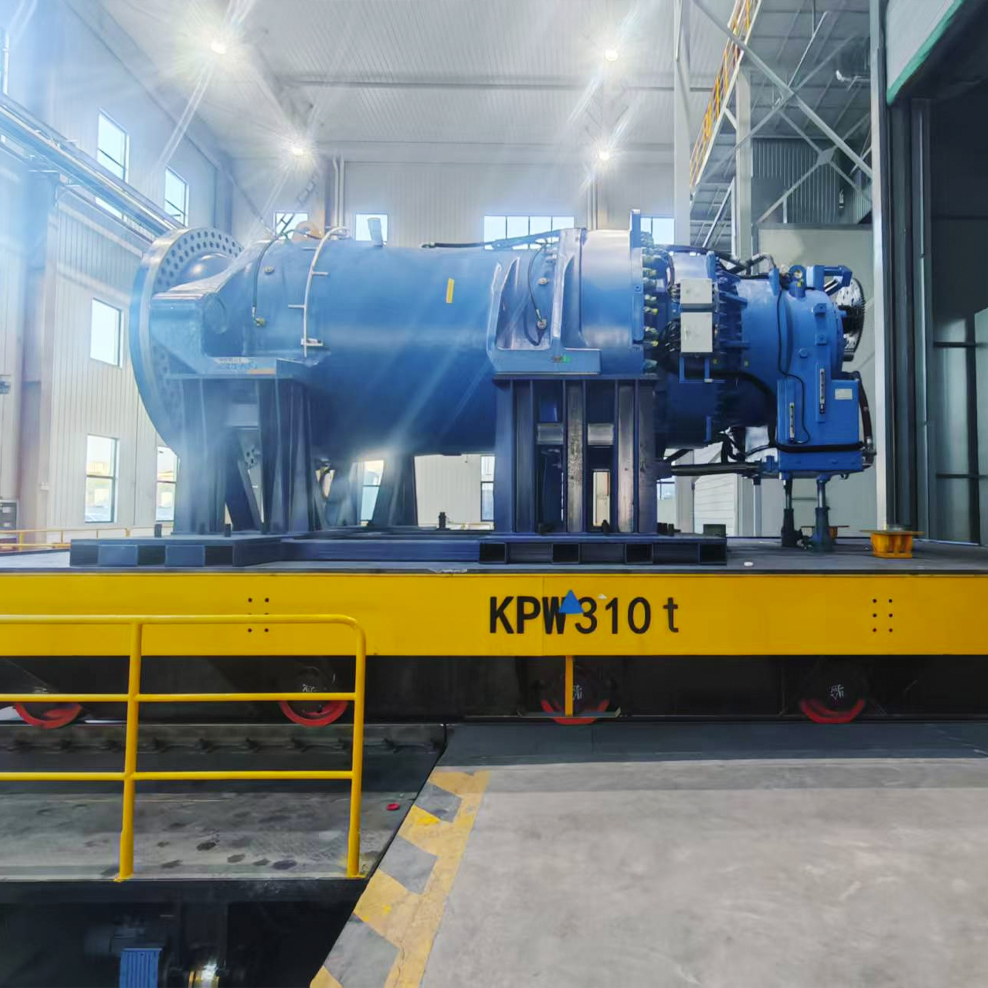 Large blue wind turbine gearbox component mounted on a heavy-duty rail transfer cart